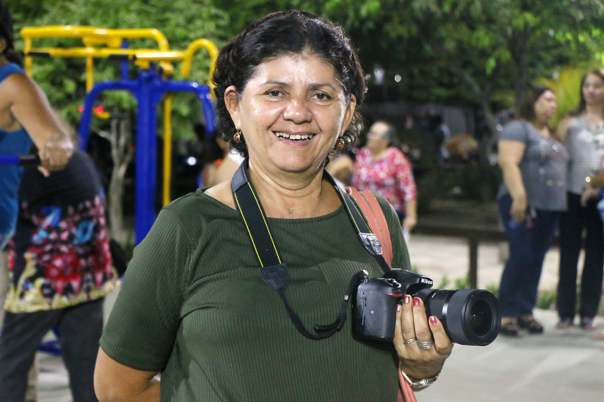 senhora sorrindo para a foto segurando uma câmera fotográfica